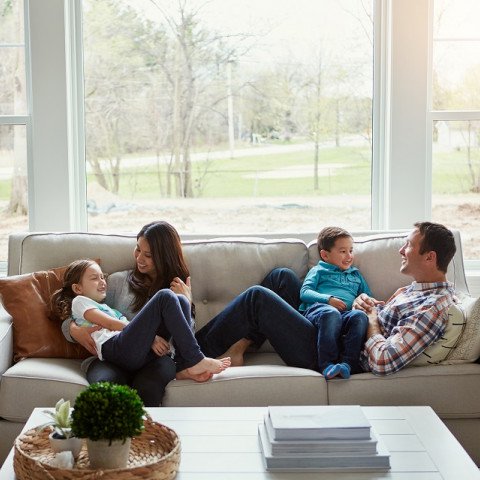 Family at home on sofa relaxing, covered by home insurance  
